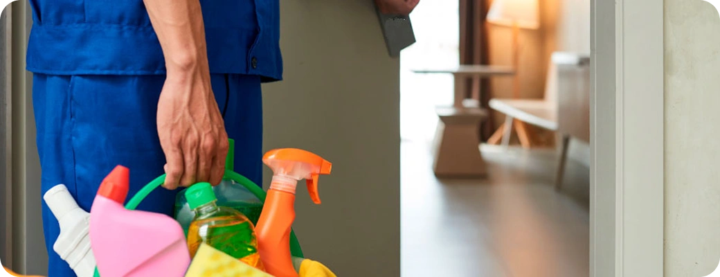 Pracownik firmy sprzątającej niosący środki czystości do sprzątania mieszkania